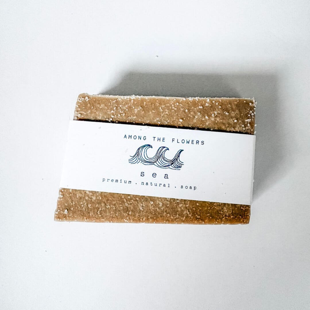 Bar of Among the Flowers 'Sea" soap with a white label on a light gray background