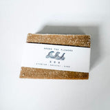 Bar of Among the Flowers 'Sea" soap with a white label on a light gray background