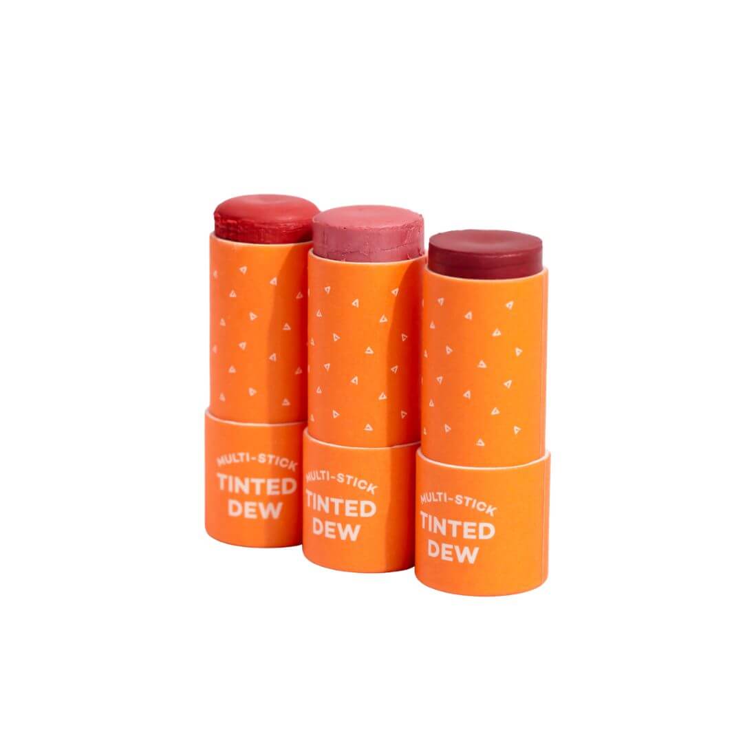 Three orange sticks of Axiology Multi-Stick Tinted Dew' on a white background