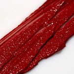 Close-up of red Axiology 'Strength"  lipstick swatch on a white background