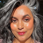 Woman with gray hair and Axiology Clarity lipstick smiling outdoors