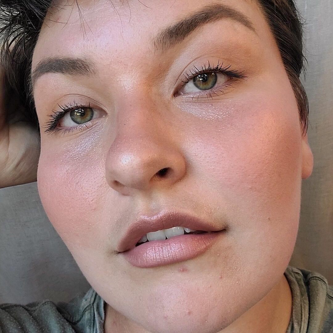 Close-up of a person wearing Axiology Peace Multi-Stick Tinted Dew