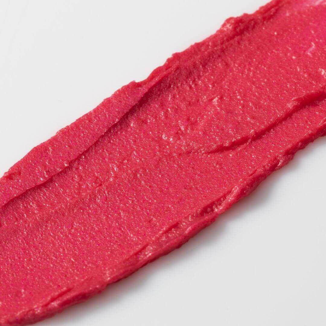 Close-up of a swatch of Axiology Tinted Dew Humble pink lipstick on a white background