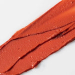 Close-up of a swatch of Axiology Tinted Dew Radiance red lipstick on a white background