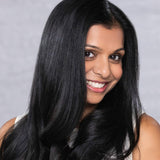 Woman with long black hair smiling against a gray background