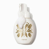 A white bottle of Fit Glow Beauty Bubble Wash with a pump dispenser, featuring a large white bubble on the front and gold foil botanical leaf designs, set against a clean white background.