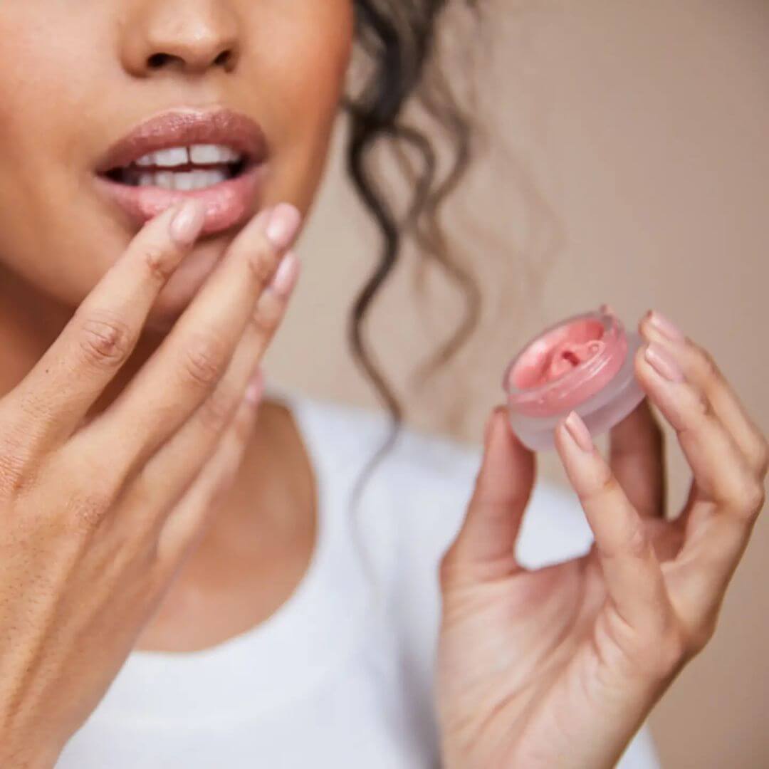 Woman holding Kari Gran Rosie Gold lip balm close to her lips.