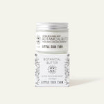 A jar of Little Seed Farm Botanical Butter shea whipped cream is stacked on top of its matching illustrated cardboard box against a solid light beige background.