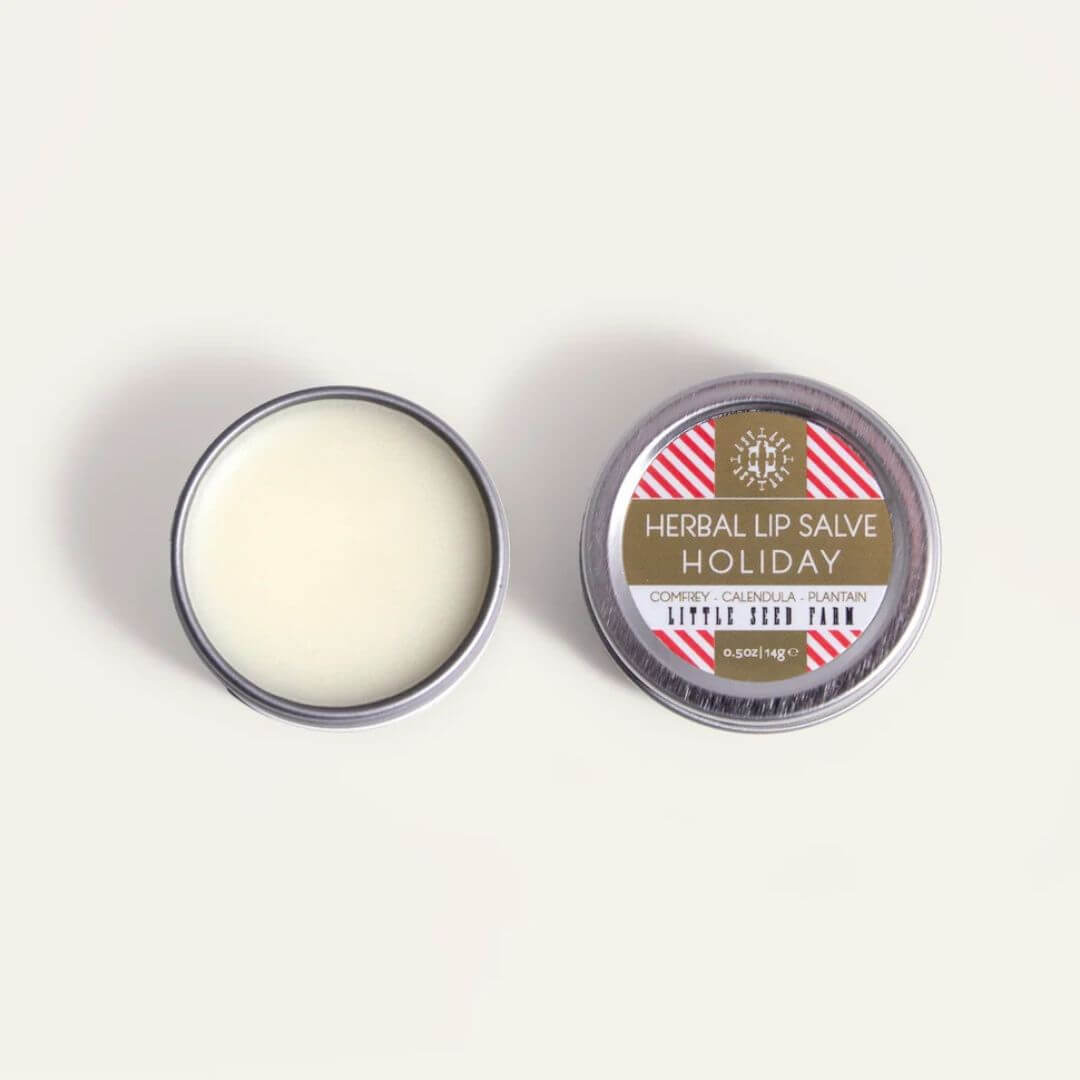An open round metal tin of Little Seed Farm Holiday lip salve 