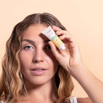 Woman holding tube of solara day dreamer peptide eye cream to her face with a beige background