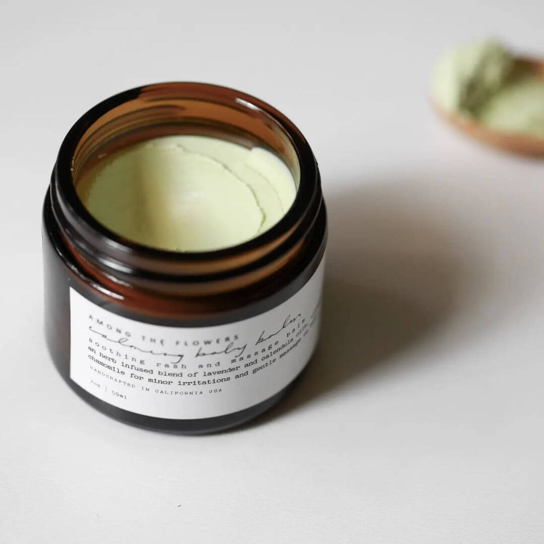 Open jar of calming baby balm cream from Among the Flowers on a white background