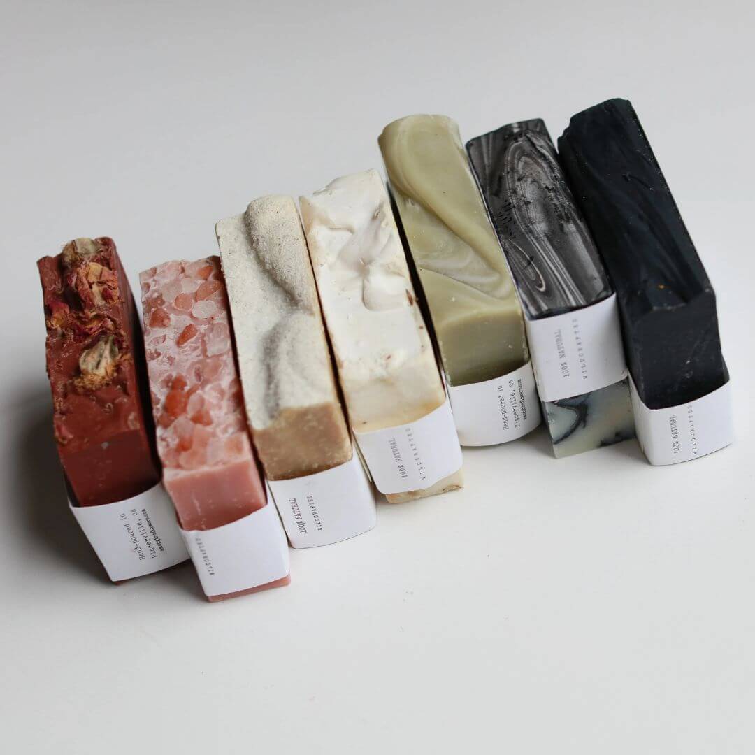 Row of Among the Flowers colored soap bars with labels on a light background