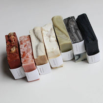 Row of Among the Flowers colored soap bars with labels on a light background