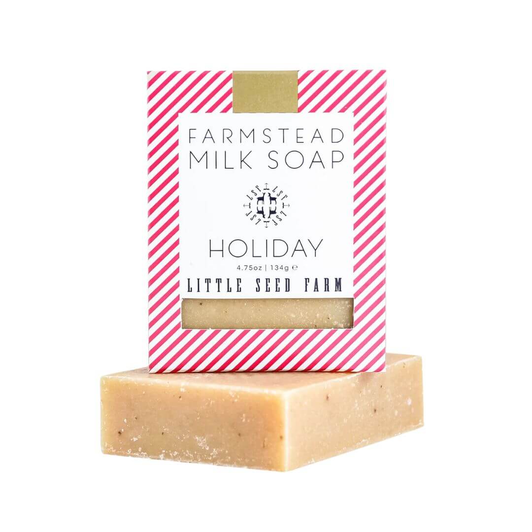 Bar of Christmas soap with a pink and white striped box labeled 'Farmstead Milk Soap' from 'Little Seed Farm' on a white background.