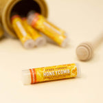 Lip balm tube labeled 'Honeycomb' by 'crazy rumors' on a beige background
