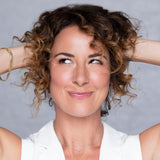 Woman with curly hair touching her hair against a gray background